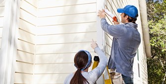 two people doing some house maintenance on the siding of the house